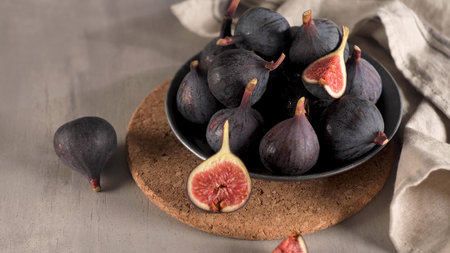 A few figs in a plate on an modern concrete counter top with dark ceramic modern vases in the background.の写真素材