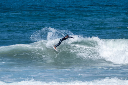 Surfer riding waves in Furadouro Beach, Portugal. Men catching waves in ocean. Surfing action water...