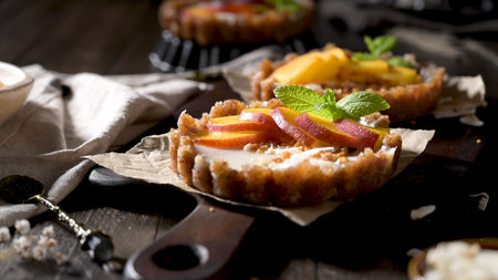 Peach vegan tarts with grated coconut  and crunchy peanuts. Fruit cake. Date, walnut, almond and hazelnut base.の写真素材