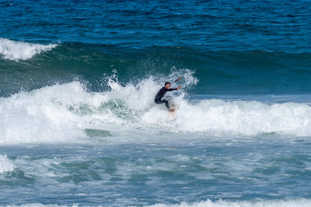Surfer riding waves in Furadouro Beach, Portugal. Men catching waves in ocean. Surfing action water board sport. people water sport lessons and beach swimming activity on summer vacation.の写真素材