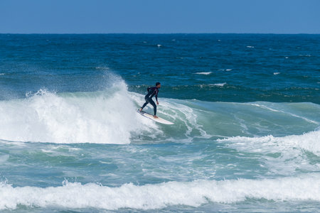 Surfer riding waves in Furadouro Beach, Portugal. Men catching waves in ocean. Surfing action water...