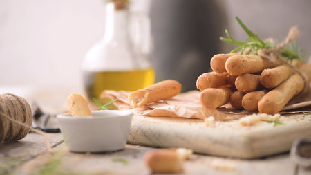 Traditional italian breadsticks grissini with rosemary, olive oil and sesame seeds on wooden...
