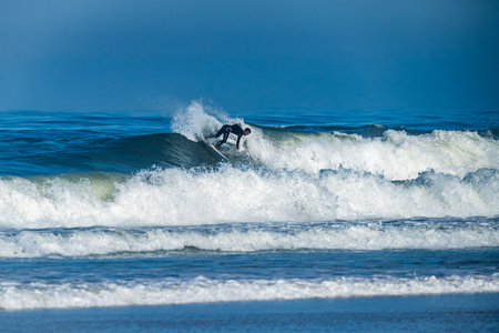 Surfer riding waves in Furadouro Beach, Portugal. Men catching waves in ocean. Surfing action water...