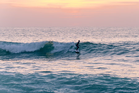 Local surfer riding waves with a short board in Furadouro beach, Portugal. Men catching waves in...