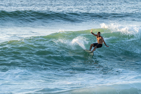 Surfer riding waves in Furadouro Beach, Portugal. Men catching waves in ocean. Surfing action water board sport. people water sport lessons and beach swimming activity on summer vacation.の写真素材