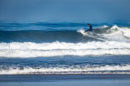 Surfer riding waves in Furadouro Beach, Portugal. Men catching waves in ocean. Surfing action water...