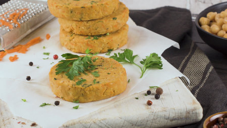 Raw veggie burger with chickpeas, vegetables and parsley leaves on kitchen countertop.の写真素材