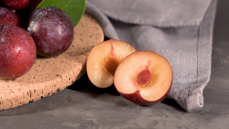 Delicious red plums in a cork plate on kitchen countertop.の写真素材