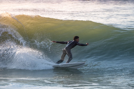 Young surfer with wetsuit enjoying big waves.