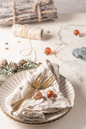 Christmas table with white plates, golden cutlery and holiday decorations.の写真素材