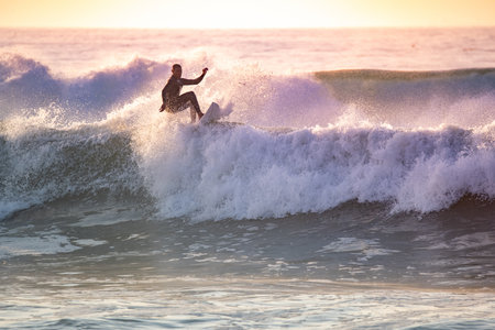 Brave teenager doing tricks on the rough sea during sunset.の写真素材