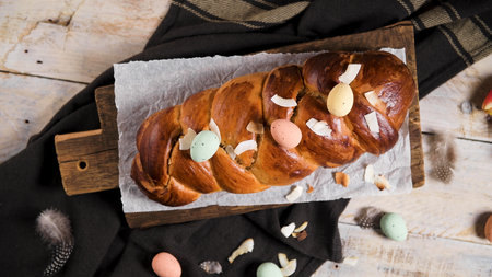 Portuguese traditional Easter cake. Folar with eggs on easter table. Blossom tulips, colorful painted eggs and feathersの写真素材