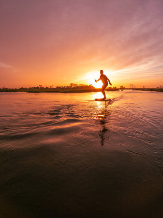 Hydrofoil rider gliding over the water with his board in one of the canals of the Ria de Aveiro in Portugal during sunset.の写真素材