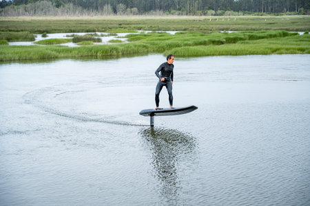 Hydrofoil rider gliding over the water with his board in one of the canals of the Ria de Aveiro in...