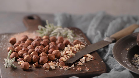 Dark chocolate truffles with hazelnuts and chopped hazelnuts over wooden cutting board.の写真素材
