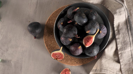 A few figs in a plate on an modern concrete counter top with dark ceramic modern vases in the...