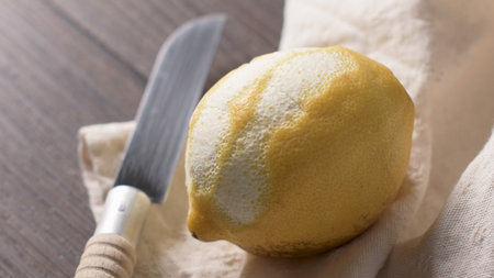 Peeled lemon fruit with knife isolated on white background.の写真素材