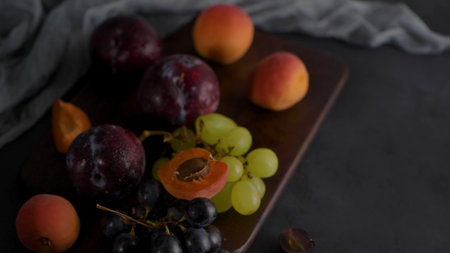 Fruits Still life with fruit on white ceramic bowl. Concrete wall. Dramatic light. Grapes, apricots...
