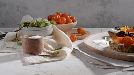 Italian bruschettas with roasted tomatoes, mozzarella cheese, pineapple slices and herbs on a rustic kitchen countertop.の写真素材