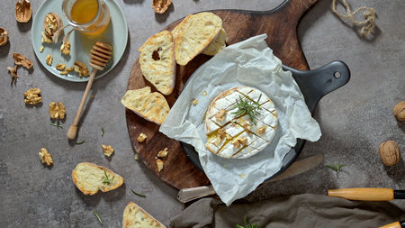 Brie type of cheese. Camembert cheese. Fresh sliced Brie cheese on a wooden tray with nuts, honey and leaves. Italian, French cheese.の写真素材