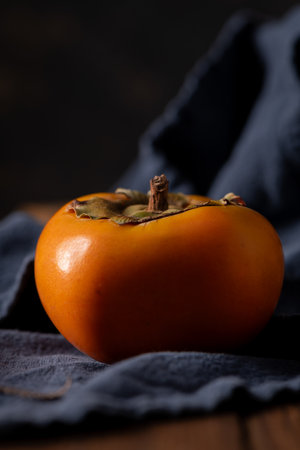 Vibrant persimmon fruit on dark backdrop with soft lightingの写真素材