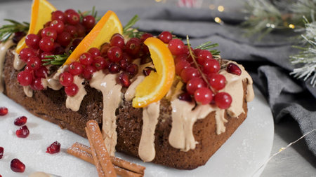 Christmas home made cinnamon cake with fruits and spekulatius cookies cream on a kitchen countertop.