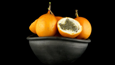 Passion fruit maracuja granadilla on ceramic black bowl, black background.の写真素材