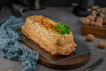 A whole molotof, a traditional caramelized egg white pudding, generously drizzled with sweet syrup and garnished with fresh mint leaves, is presented on a glass serving trayの写真素材