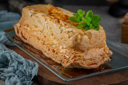 A whole molotof, a traditional caramelized egg white pudding, generously drizzled with sweet syrup and garnished with fresh mint leaves, is presented on a rectangular glass dishの写真素材