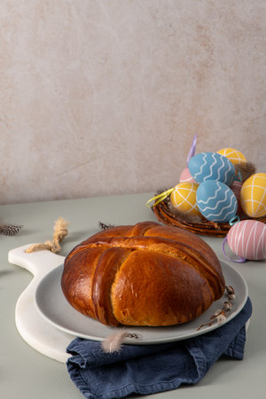 Golden brown traditional folar cake on a plate with Easter eggs in a basket and pussy willow branches, symbolizing springtime and festive bakingの写真素材