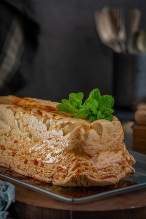 A whole molotof, a traditional caramelized egg white pudding, generously drizzled with sweet syrup and garnished with fresh mint leaves, is presented on a glass serving plateの写真素材