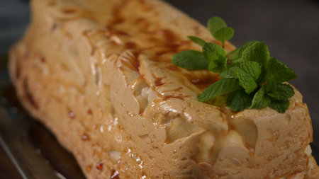 A tempting molotov pudding, its golden caramel glaze contrasting with the light meringue, beautifully garnished with fresh green mint leaves.の写真素材