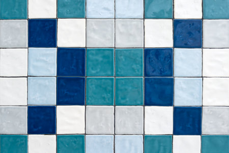 A vibrant mosaic of square ceramic tiles in diverse shades of blue, white, and teal, forming an...