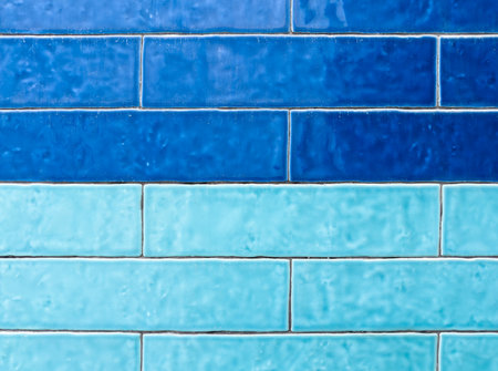 A textured wall showcases two distinct horizontal rows of rectangular tiles: a darker blue on top and a lighter, vibrant turquoise below.の写真素材