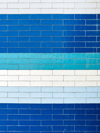 A textured wall featuring rectangular tiles in a mosaic of various blue and white shades, creating a harmonious and classic pattern.の写真素材