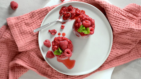 A top-down view of two small jars of creamy chia seed pudding, generously topped with a rich...