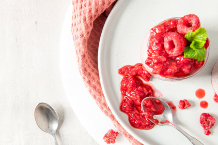 A close-up, top-down view of a single jar of raspberry chia seed pudding on a white plate. The focus...