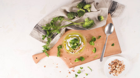 Broccoli soup in a glass bowl on a kitchen countertop with slices of the stems.の写真素材