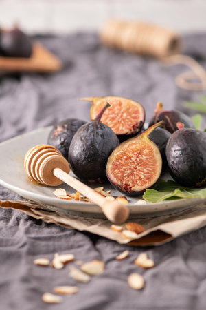 A rustic still life of fresh Black Mission figs, some whole and some cut in half to reveal their...