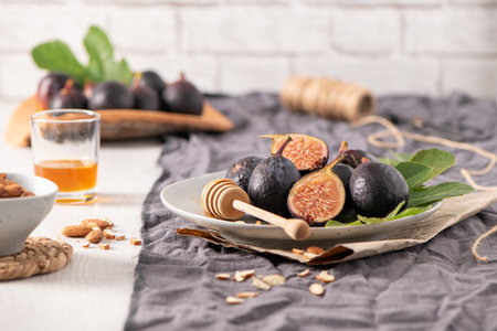 A rustic still life of fresh Black Mission figs, some whole and some cut in half to reveal their...