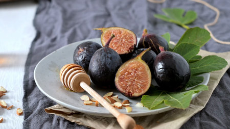 A rustic still life of fresh Black Mission figs, some whole and some cut in half to reveal their...