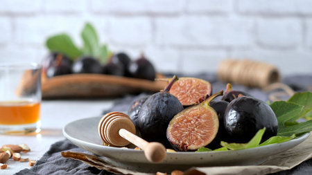 A rustic still life of fresh Black Mission figs, some whole and some cut in half to reveal their vibrant red flesh.の写真素材