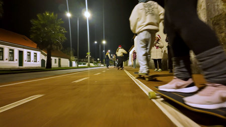 OVAR, PORTUGAL - DECEMBER 23, 2025: Participants wearing Santa hats ride skateboards through the festive pedestrian streets.のeditorial素材