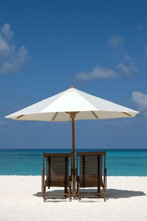 Beach chairs and umbrella on a sand beach in Maldivesの写真素材