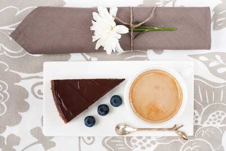 Chocolate tart with bilberry and a cup of coffee on a cute table appointmentsの写真素材