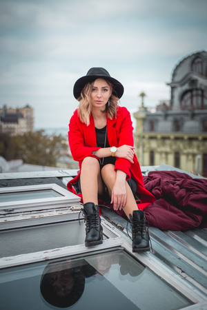 Girl in red and with black hat posing on the roof of old city.の写真素材
