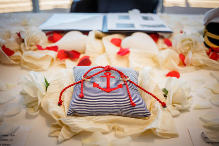 Wedding golden rings together with red rope on striped pillow with anchor on it. Marriage ceremonyの写真素材