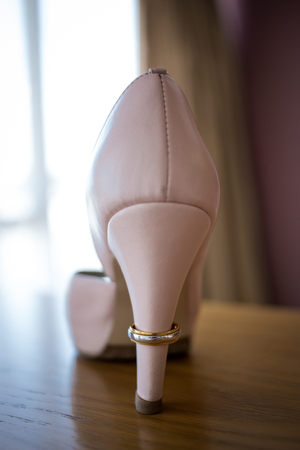 Wedding golden ring on the heel of brides pink shoe. Ceremonyの写真素材