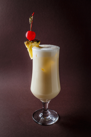 Glass of pina colada with berry and pineapple on elegant dark brown background.の写真素材