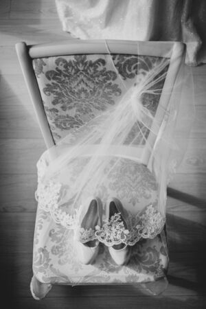 Bridal high heel shoes for happy wedding under veil on the chair. BW Black and white.の写真素材